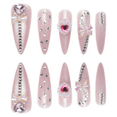 Pink cat eye press-on nails in long stiletto style, adorned with rhinestones and bows for a glamorous look.